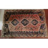 A Persian carpet with triple hooked central medallions with stylised bird motifs on the madder