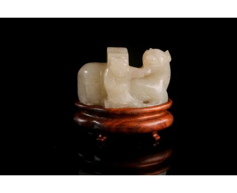 A Chinese carved pale celadon green jade figure of a boy trying to raise his laden, recumbent packhorse. On a carved hardwood