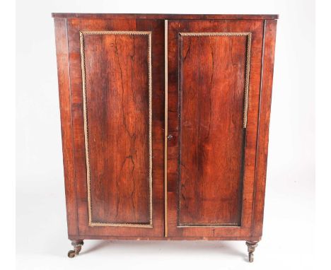 An early Victorian gilt metal mounted figured rosewood two-door collectors cabinet, the doors opening to reveal a bank of thi