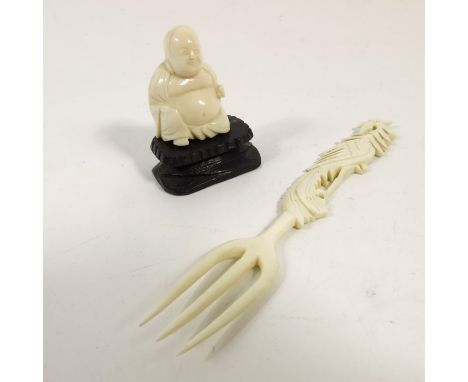 λ A 19th century Japanese ivory okimono, modelled as a sitting Buddha, together with a Chinese fork, 14cm long (2)