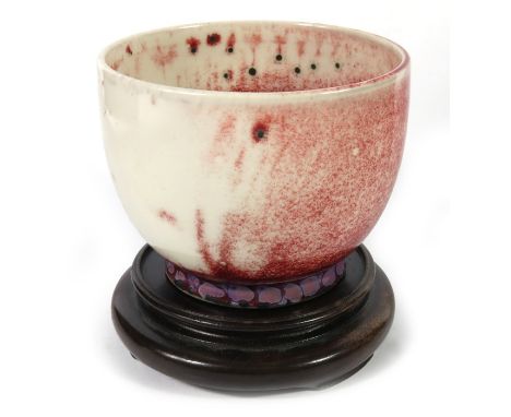 A Ruskin high fired bowl, circa 1920, white and red with black spots, impressed marks, 6.5cm high, 8.5cm diameter, on wooden 