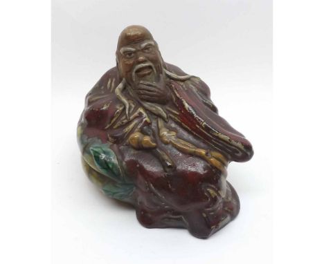 A Chinese Pottery Figure of a reclining wise man in a pensive pose, painted predominantly in red with famille verte detail, s