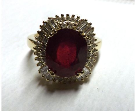 A mid-grade precious metal centre Ruby (5 .40ct) and Diamond surround Cluster Ring, the baguette and Brilliant Cut Diamonds a