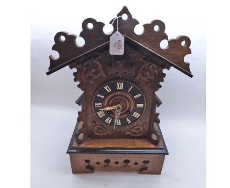 A late 19th Century Oak and ebonised Mantel Cuckoo Clock, the architectural case with carved and pierced pediment on a plinth