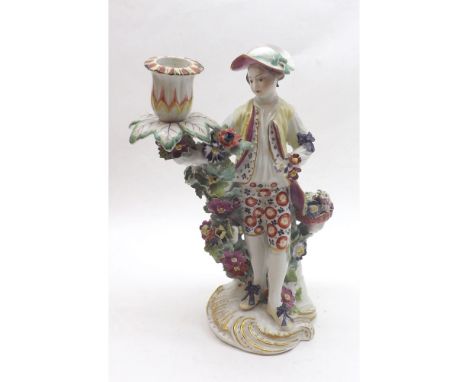English Porcelain Candlestick figure of a male flower seller painted in colours throughout and encrusted with flower sprays e