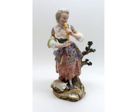 A Meissen Figure of shepherdess playing a recorder and with a lamb at foot, standing beside a tree stump, painted in colours 