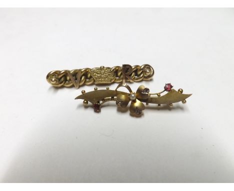 A late Victorian hallmarked 9ct Gold Bar Brooch of scroll design, with flower head centre set with two red stones and a seed 