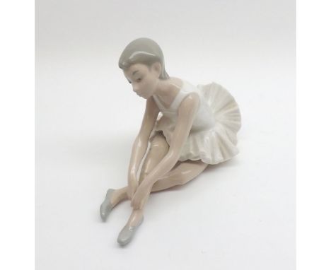 A Nao Figure of a young seated ballerina wearing a tutu, 6 1/2" high 