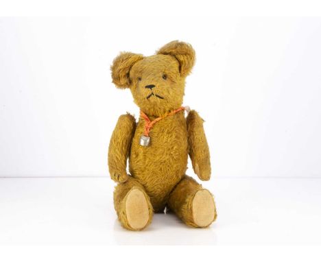 A 1930's teddy bear possibly French, with dark golden mohair, black boot button eyes, black stitched nose, mouth and claws, s