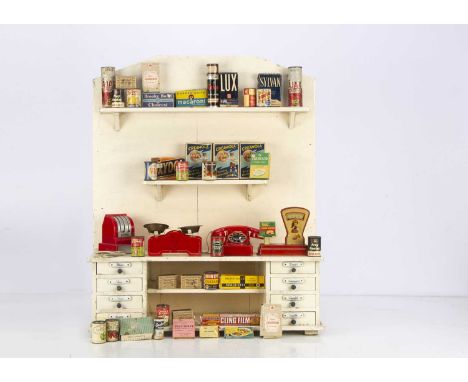 A painted wooden toy shop,  repainted cream with eight drawers with porcelain labels —22 1/2in. (57cm.) high; a tinplate scal