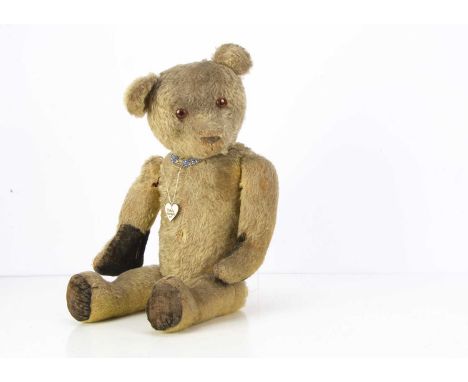 A German 1920's teddy bear, with light golden mohair, orange and black glass eyes, black stitched nose and mouth, swivel head