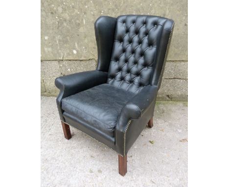 A 20th Century Wingback Armchair with a button upholstered back and drop in seat raised upon square legs