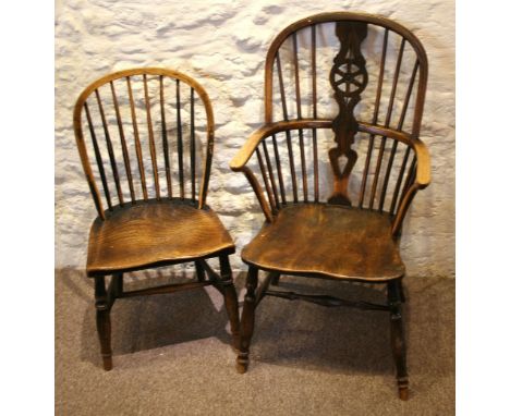 An Early 19th Century Elm Windsor Armchair with a wheel splat back above a panelled seat raised upon turned legs with stretch