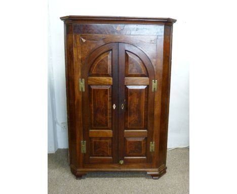 A George III Mahogany Standing Corner Cabinet, the moulded cornice above two arched doors enclosing shelves raised upon ogee 