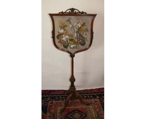 A William IV Mahogany Fire Screen, the tapestry beadwork panel depicting a peacock amongst foliage, raised upon a turned cent
