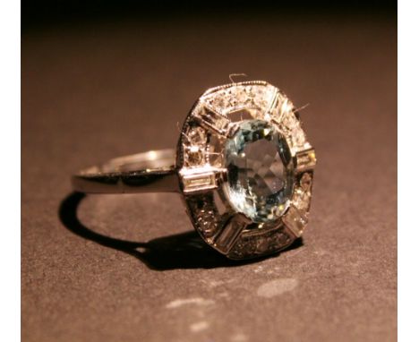 An 18ct. White Gold Aquamarine and Diamond Ring, with a central oval aquamarine surrounded by diamonds