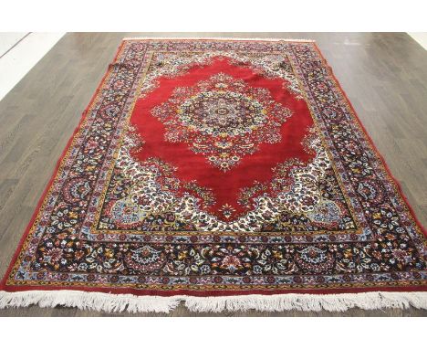 A North West Persian Woollen Carpet with a central medallion within an all-over design upon a red and blue ground within mult