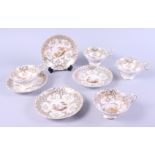Four 19th century white, grey and gilt decorated cups and saucers, with hand-painted rural scenes to