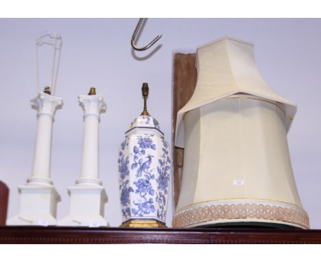 A pair of white china Corinthian column table lamps, a similar blue and white ginger jar lamp, two cream standard lamp shades