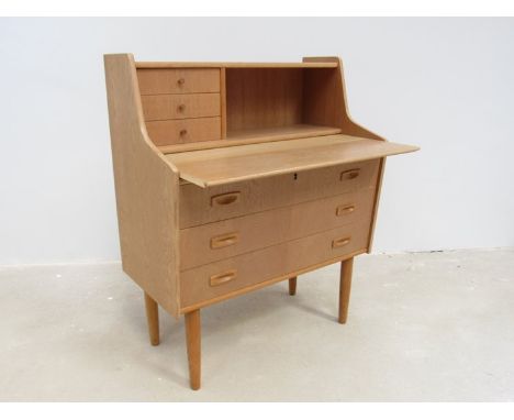 A Danish light oak bureau, pull out writing surface with three long drawers below three small drawers above. Raised on taperi