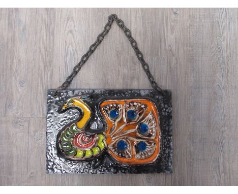 A West German ceramic wall hanging plaque depicting a raised peacock design in a variety of colours.  25cm x 37.5cm