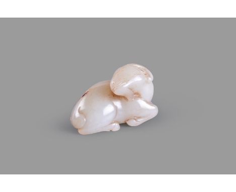 A white and russet jade carving of a ram, the recumbent ram carved with its head turned towards the back and its legs neatly 