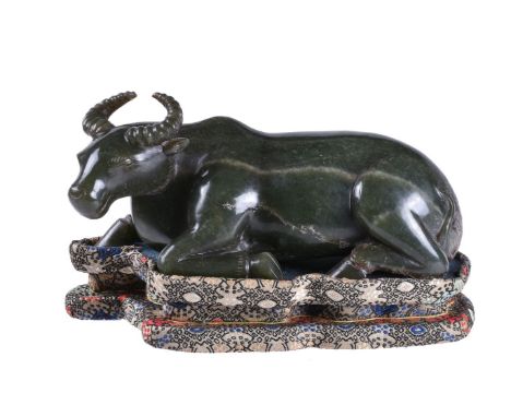 A Chinese spinach green jade carving of a buffalo, with white and other coloured inclusions to the stone, 19cm long, fitted f