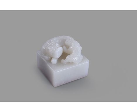 A Chinese white jade seal, 20th century, modelled with a lion and pup, carved seal to underside, 5.2cm high x 6.2cm square 白玉