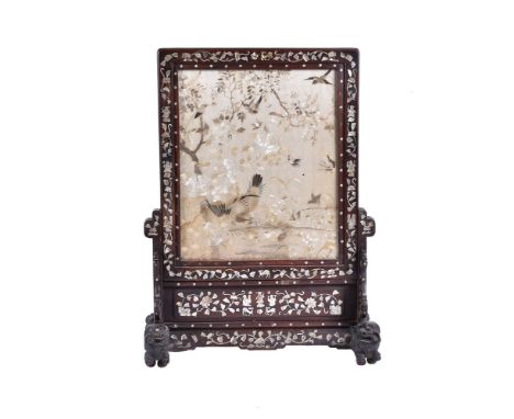 ϒA Chinese hardwood embroidered screen, circa 1900, inlaid within a mother-of-pearl, supported on two Buddhist lion feet, 67c