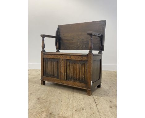 An oak monks bench of 18th century design, the folding top over open arms with turned columns, hinged seat opening to a plain