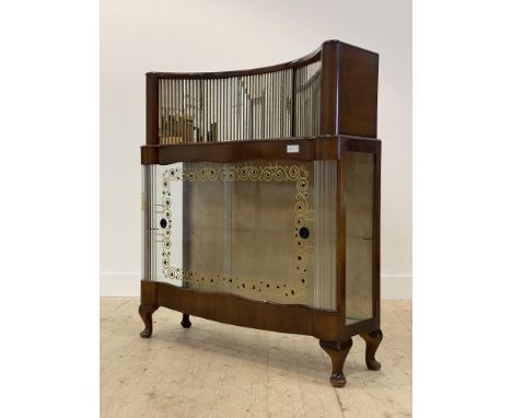 An Art Deco walnut cocktail cabinet, circa 1930's, the concave superstructure with sliding mirrored doors above further slidi