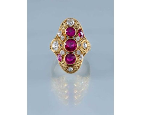 A RUBY AND DIAMOND COCKTAIL RING, the domed oval panel centred by three facet cut rubies collet set to an open cannatille gro