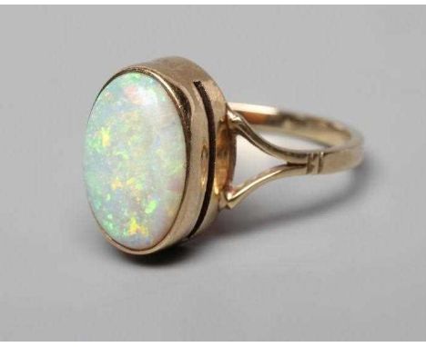AN OPAL DRESS RING, the oval cabochon polished stone collet set to open shoulders and a plain 9ct gold shank, Birmingham 1987