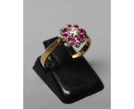 A RUBY AND DIAMOND CLUSTER RING, the central round brilliant cut diamond of approximately 0.60cts to a border of eight small 