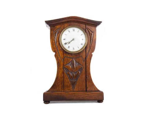 ARTS &amp; CRAFTS OAK MANTEL CLOCK LATE 19TH CENTURY the white enamel dial set with Roman numerals, the carved balloon-shaped