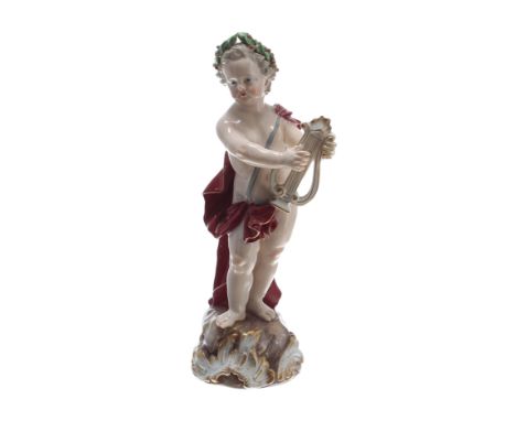 Meissen porcelain figure of a Putto, modelled standing playing a lyre, wearing a red cape and laurel leaf headdress, with und