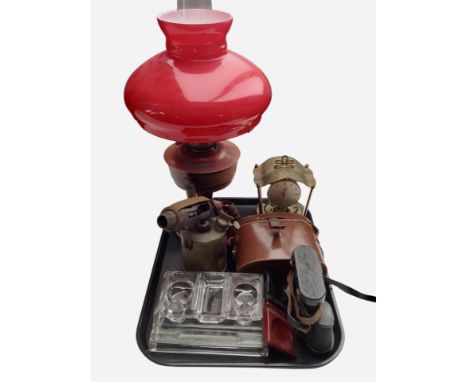 An oil lamp with red glass shade, together with a vintage low lamp, a glass dressing table stand, a pair of BNK binoculars.