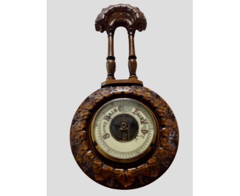 A heavily carved beech barometer, length 43cm.