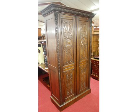 A good circa 1900 joined and relief carved oak double door side cupboard, having acanthus leaf carved ogee cornice over twin 