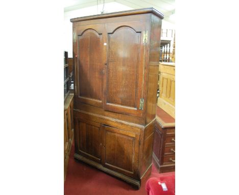 An 18th century joined oak four door housekeeper's cupboard, having upper arched recessed panel doors, enclosing painted shel