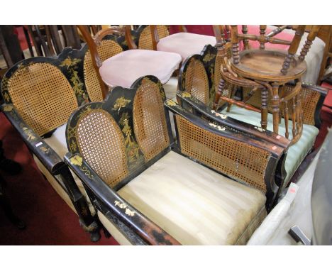 An early 20th century chinoiserie black lacquered and cane inset three-piece Bergere suite, comprising three-seater sofa and 