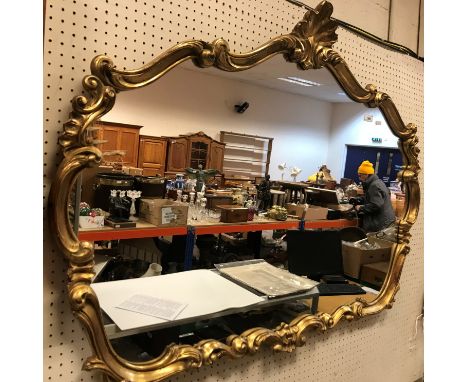 A 20th Century gilt framed wall mirror with scallop shell finial and C scrolling decoration 90 cm x 120 cm