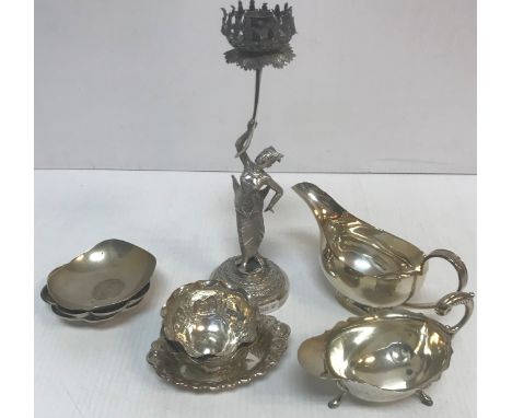 An Indian white metal sauce boat with spoof marks, a plated sauce boat, Thai or Burmese white metal figural candlesticks, two