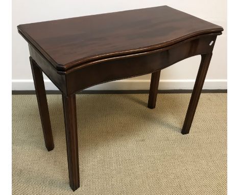 An Edwardian mahogany serpentine fronted fold-over card table in the George III taste, the top with moulded edge above a rope