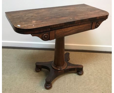 An early Victorian rosewood fold-over card table on tapering turned pedestal to platform quadruped base, bun feet and castors