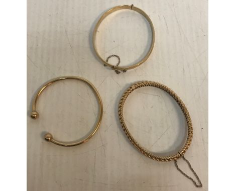 A 15 carat gold bangle with stylised rope decoration 14 g together with one 9 carat gold bangle in the style of a Roman torq 