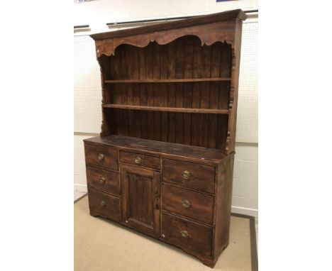 A 19th Century stained pine dresser, the boarded two tier plate rack over a central drawer and cupboard door flanked by two b