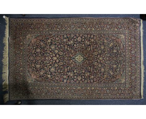 A 20th century Kashan rug with a flower-filled "Bookcover" scheme on a dark blue ground. Within a palmeted border and fringed