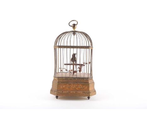 An early 20th century singing bird automaton, in a gilded cage, the base with moulded foliate decoration, on four feet, 27cm 