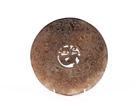 A Chinese carved russet/kahki jade Bi disc carved with tigers, dragons, and phoenix on a cloud-filled ground. 22 cm diameter.